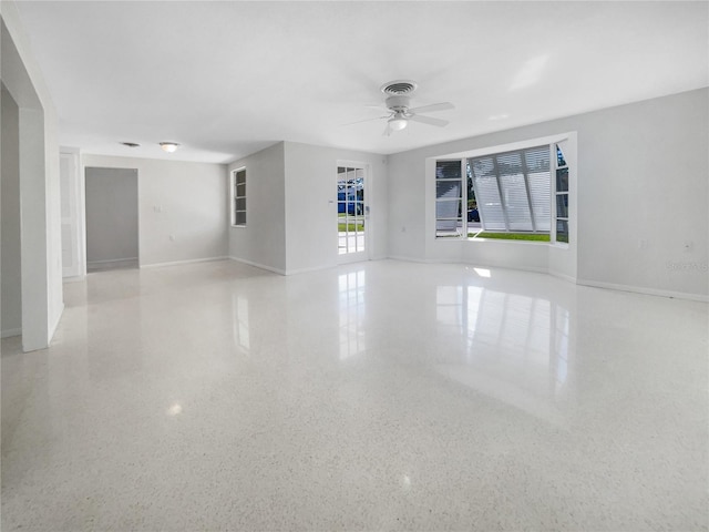 spare room with visible vents, a ceiling fan, speckled floor, and baseboards