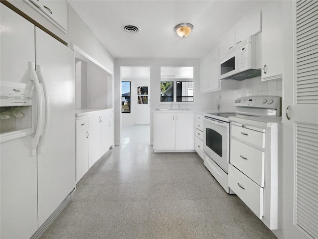 kitchen with visible vents, white appliances, white cabinetry, and light countertops