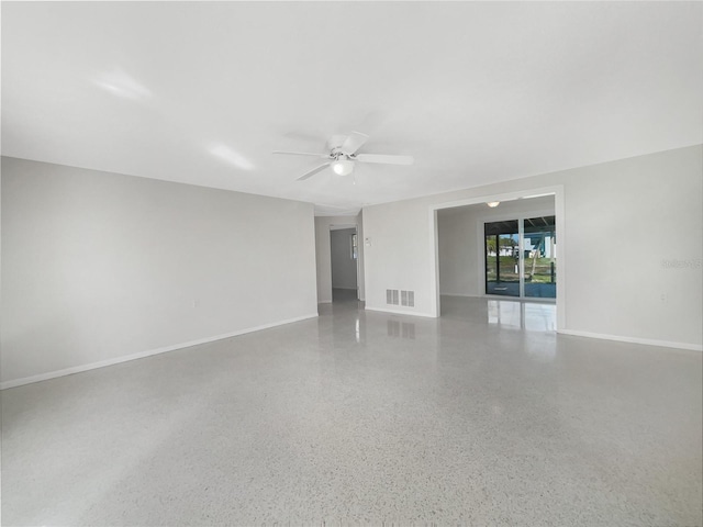 unfurnished room featuring speckled floor, baseboards, visible vents, and ceiling fan