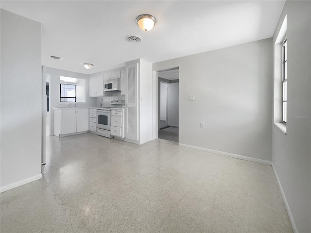 kitchen with white appliances, white cabinets, baseboards, and visible vents