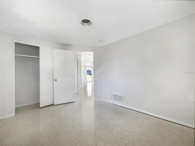 unfurnished bedroom featuring a closet, visible vents, speckled floor, and baseboards