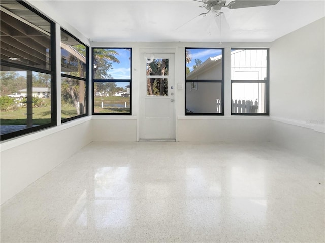 spare room with speckled floor, plenty of natural light, and a ceiling fan