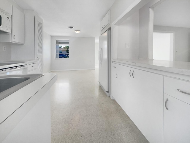 hall featuring visible vents, light speckled floor, and baseboards