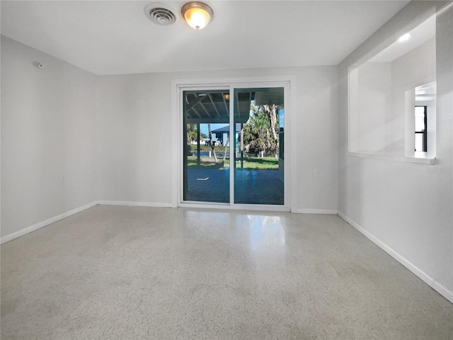 spare room with visible vents, speckled floor, and baseboards