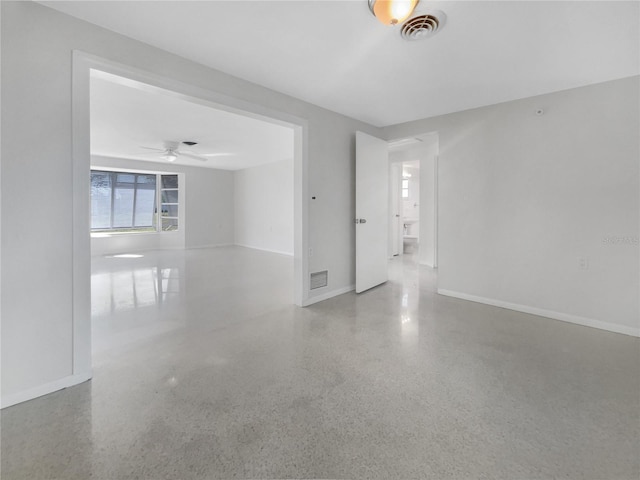 empty room with speckled floor, baseboards, visible vents, and ceiling fan