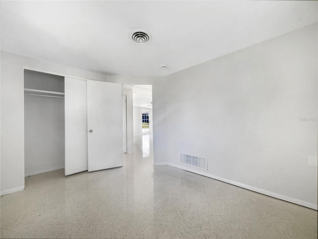 unfurnished bedroom featuring visible vents, speckled floor, and baseboards