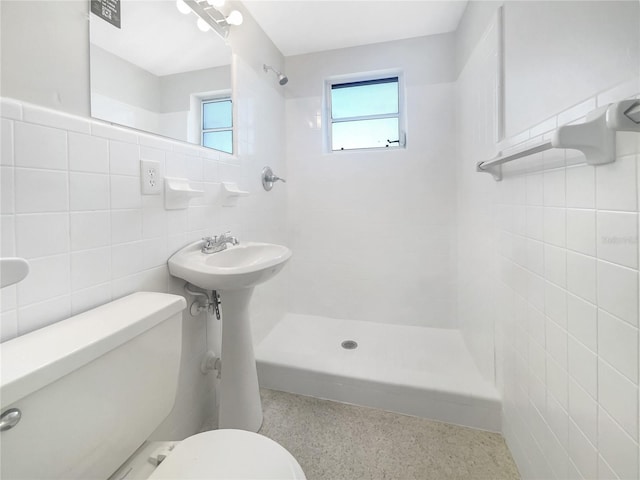 bathroom featuring tile walls, toilet, speckled floor, and tiled shower