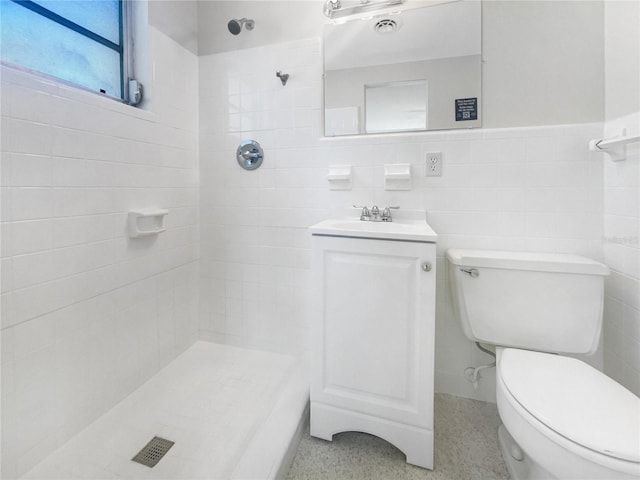 bathroom with a tile shower, toilet, tile walls, and speckled floor