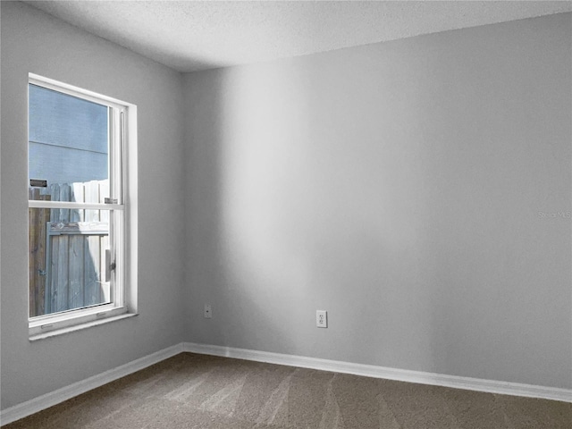 unfurnished room with baseboards, carpet floors, and a textured ceiling