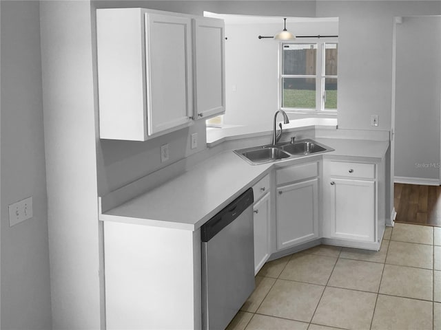 kitchen with light tile patterned floors, a sink, light countertops, white cabinets, and dishwasher