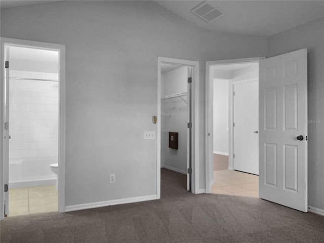 unfurnished bedroom featuring visible vents, carpet floors, a spacious closet, a closet, and tile patterned floors