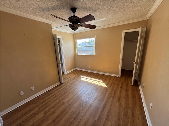 unfurnished bedroom featuring a textured ceiling, wood finished floors, baseboards, and ornamental molding