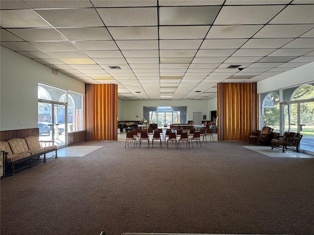 unfurnished dining area with carpet flooring, visible vents, and a drop ceiling