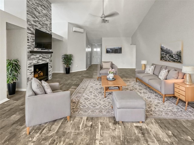 living room with wood finished floors, visible vents, baseboards, ceiling fan, and a stone fireplace