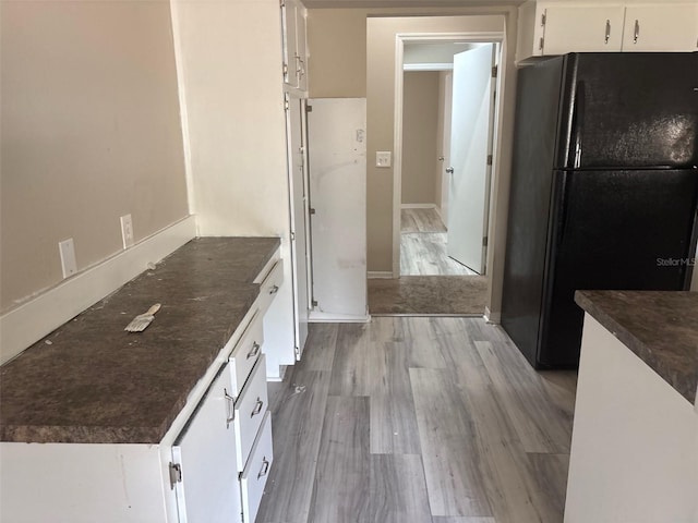 kitchen featuring white cabinetry, dark countertops, light wood-style floors, and freestanding refrigerator