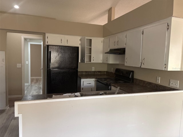 kitchen featuring light wood-type flooring, black appliances, under cabinet range hood, dark countertops, and a peninsula