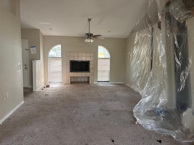 unfurnished living room featuring carpet, a healthy amount of sunlight, ceiling fan, and a tile fireplace