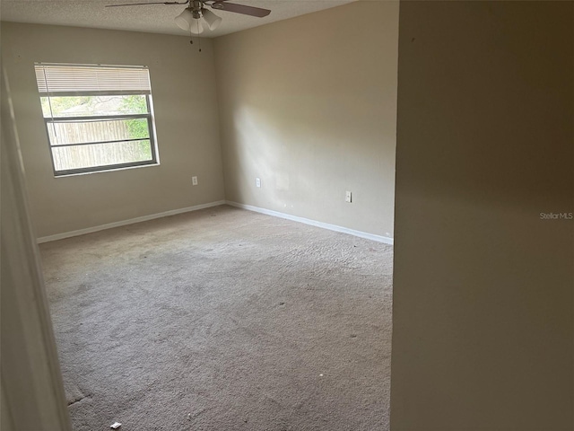 carpeted empty room with a textured ceiling, baseboards, and ceiling fan