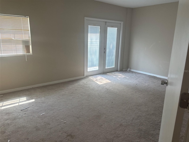 spare room featuring carpet, french doors, and baseboards