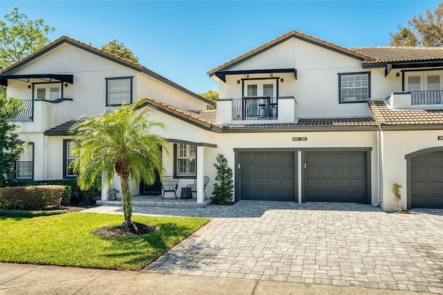 view of front of home featuring a balcony, an attached garage, stucco siding, a tile roof, and decorative driveway