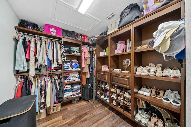 walk in closet with attic access, wood finished floors, and visible vents