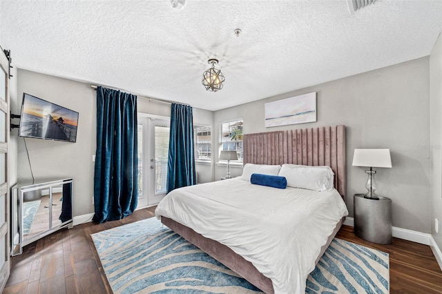 bedroom with visible vents, access to outside, a textured ceiling, wood finished floors, and baseboards