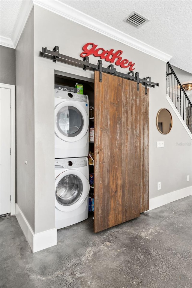 washroom featuring visible vents, a barn door, laundry area, a textured ceiling, and stacked washer / drying machine