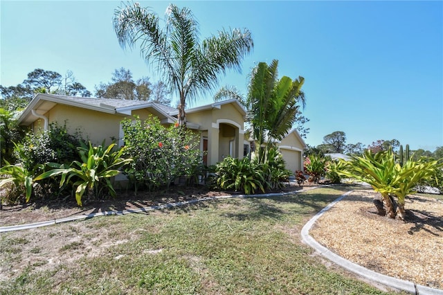 view of front of home with stucco siding, a front lawn, and a garage