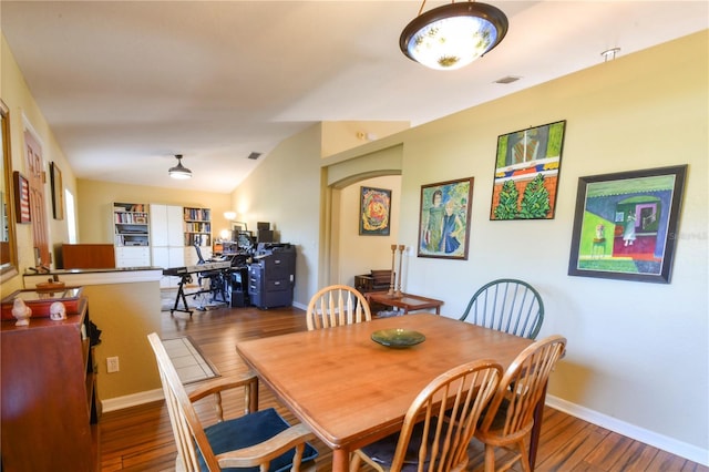 dining space featuring visible vents, baseboards, arched walkways, and wood finished floors