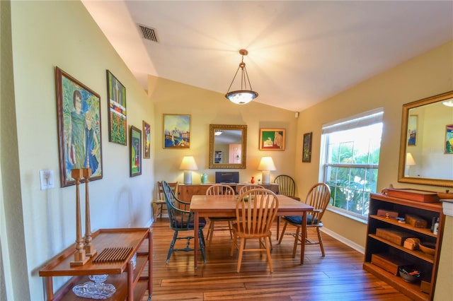 dining room featuring visible vents, lofted ceiling, baseboards, and hardwood / wood-style flooring