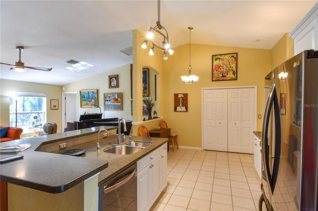 kitchen with dark countertops, vaulted ceiling, dishwashing machine, freestanding refrigerator, and a sink