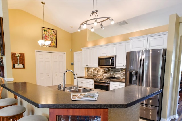 kitchen featuring a breakfast bar, a sink, stainless steel appliances, vaulted ceiling, and dark countertops