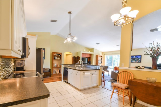 kitchen with dishwashing machine, dark countertops, open floor plan, and a chandelier