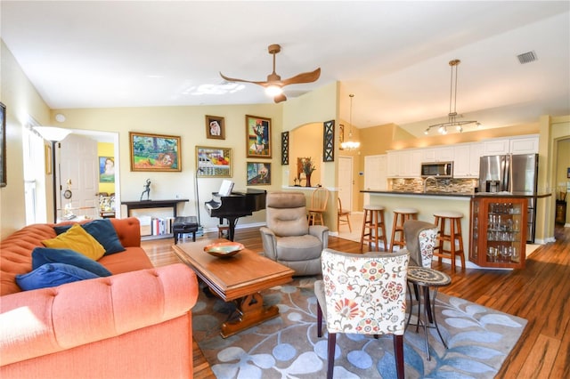 living room with vaulted ceiling, visible vents, dark wood-type flooring, and ceiling fan