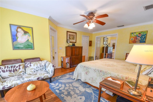 bedroom with crown molding, wood finished floors, visible vents, and a closet