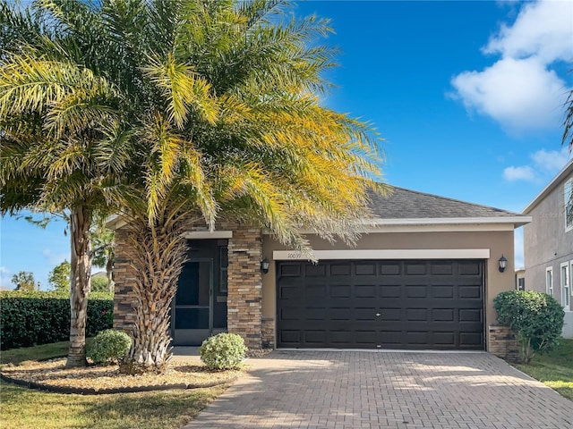 view of front of house with stone siding, stucco siding, decorative driveway, and a garage