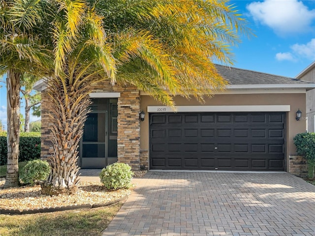 view of front of property with stone siding, stucco siding, decorative driveway, and roof with shingles