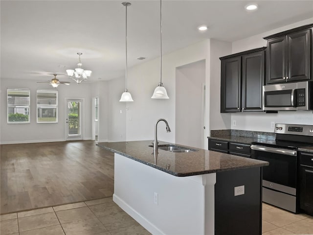 kitchen with a sink, stainless steel appliances, dark stone countertops, and light tile patterned floors