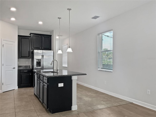 kitchen featuring visible vents, dark cabinets, dark stone counters, and a sink