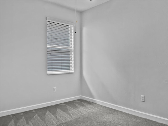 spare room with baseboards and dark carpet