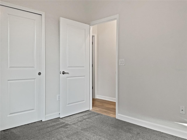 unfurnished bedroom with a closet, carpet flooring, and baseboards