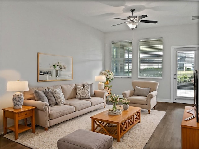 living area featuring visible vents, baseboards, dark wood finished floors, and a ceiling fan