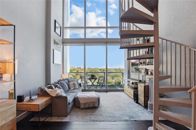 living area featuring expansive windows, a high ceiling, wood tiled floor, and a textured wall