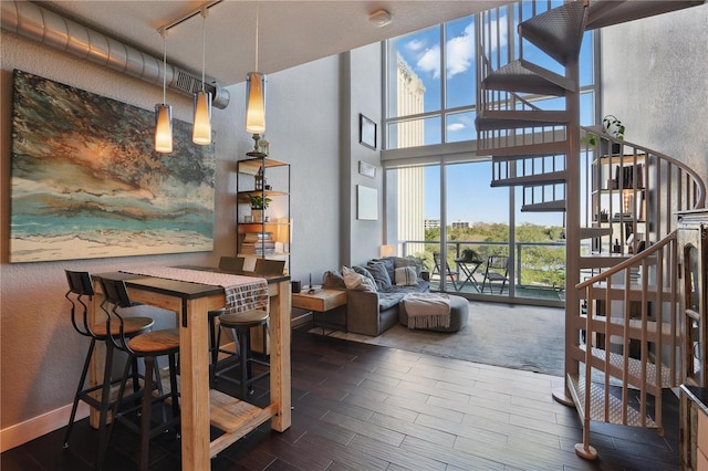 dining area featuring stairway, wood finish floors, a high ceiling, rail lighting, and a textured wall