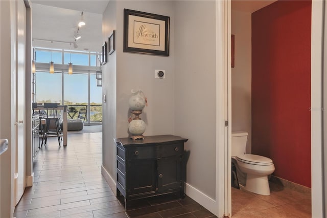 hall featuring floor to ceiling windows, rail lighting, and baseboards