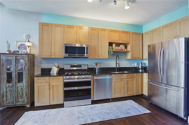 kitchen with light brown cabinets, stainless steel appliances, wood tiled floor, and a sink