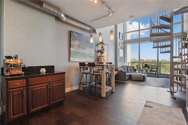 dining space featuring rail lighting, baseboards, and wood tiled floor