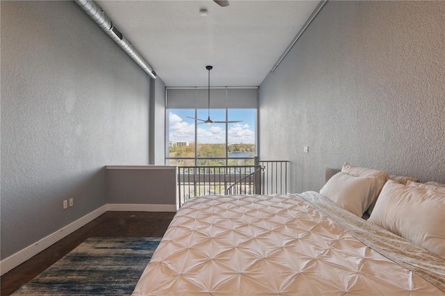 bedroom featuring access to exterior, wood finished floors, a textured wall, and baseboards