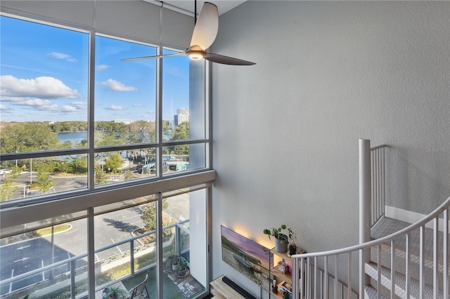 stairway featuring a textured wall, a ceiling fan, and a water view