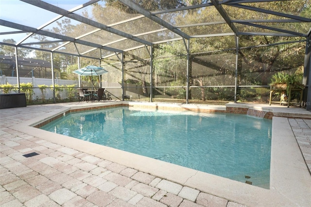 pool with glass enclosure, a patio area, and fence